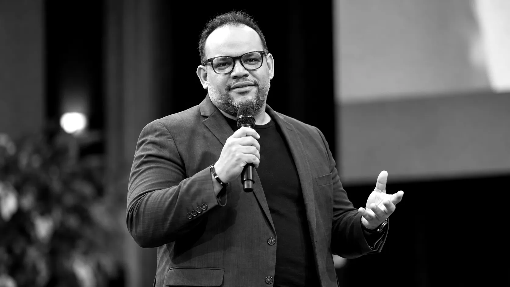 Alf Álvarez dando una charla en un escenario, micrófono en mano