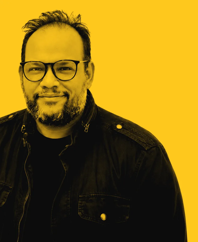 Retrato de Alf Álvarez con lentes y chaqueta negra, sonriendo